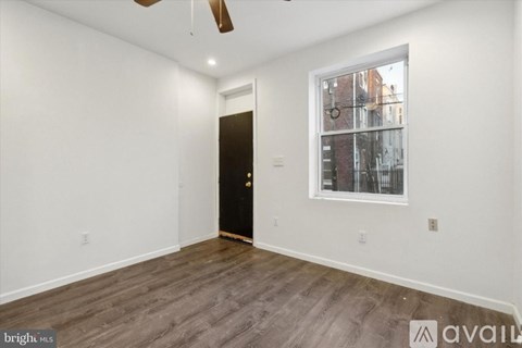 A room with a black door and a window showing a view of a street.