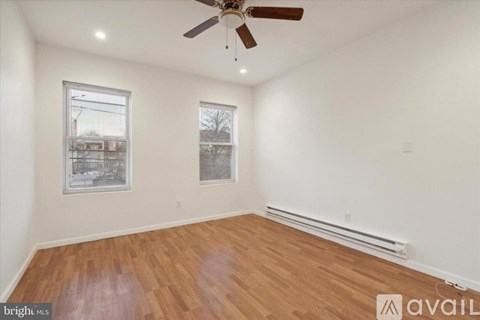A room with a ceiling fan and two windows.