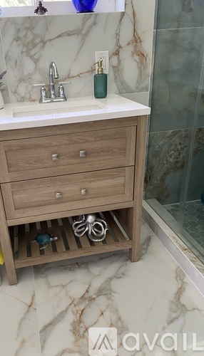 A bathroom vanity with a marble countertop and a wooden drawer.