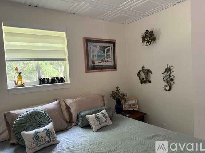 A bedroom with a bed, pillows, and a window with blinds.