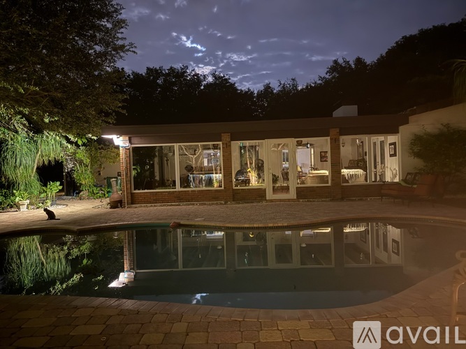 A house with a pool in front of it at night.
