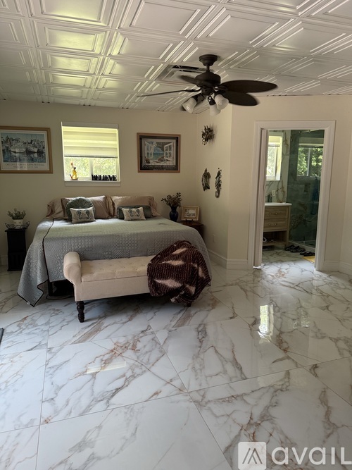 A bedroom with a bed, a ceiling fan, and a marble floor.