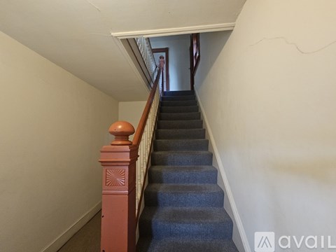 A staircase with a blue carpeted runner and wooden balusters.