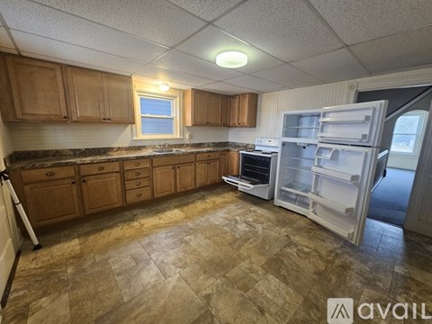 A kitchen with a tile floor and a refrigerator with the door open.