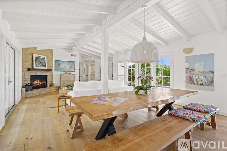 A spacious room with a wooden table and benches, a fireplace, and a painting on the wall.