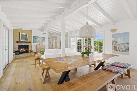 A spacious room with a wooden table and benches, a fireplace, and a painting on the wall.