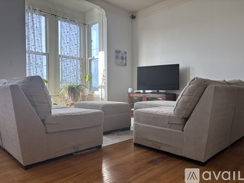 Two grey couches in a living room with a television and a window.