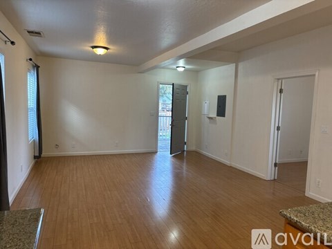 A spacious room with wooden flooring and white walls.