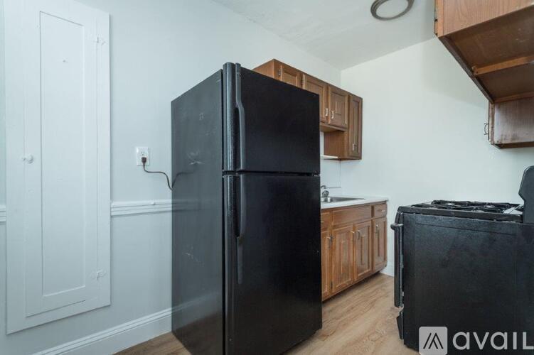 A black refrigerator in a kitchen with wooden cabinets.