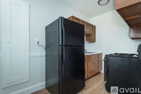 A black refrigerator in a kitchen with wooden cabinets.