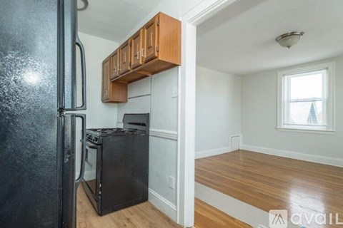 A kitchen with a black fridge and wooden cabinets.