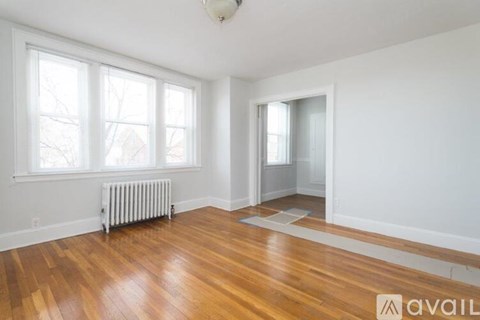 A room with wooden floors and a window with a view of trees.