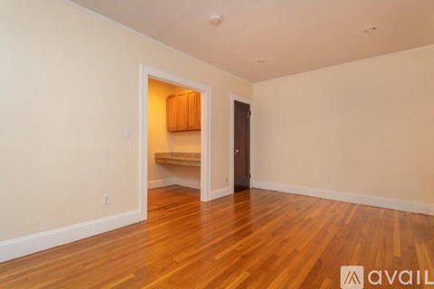 A room with wooden floors and a doorway leading to another room.