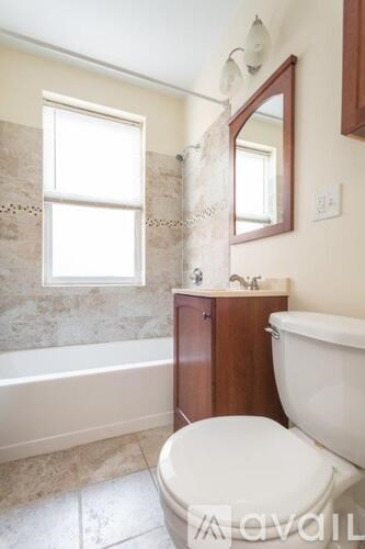 A bathroom with a toilet, tub, and mirror.