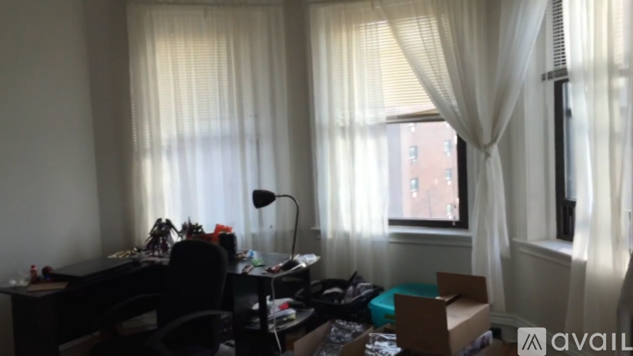 A room with a desk, chair, and a window with curtains.