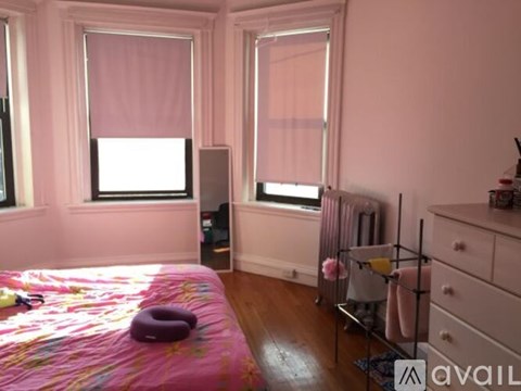 A bedroom with a bed, a dresser, and a window with blinds.