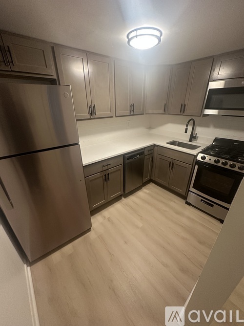 A kitchen with a stainless steel refrigerator and wooden floors.