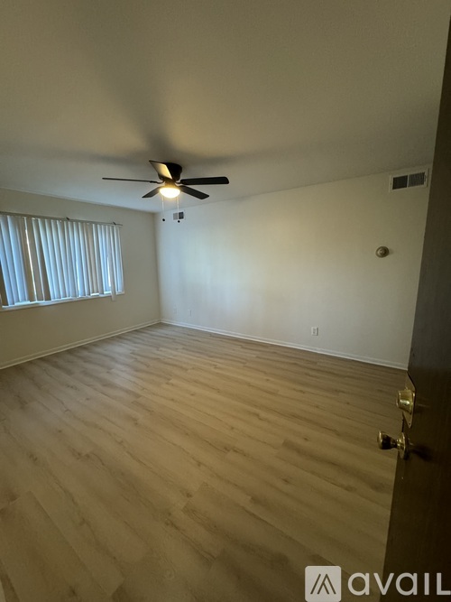 A room with a ceiling fan and wooden flooring.