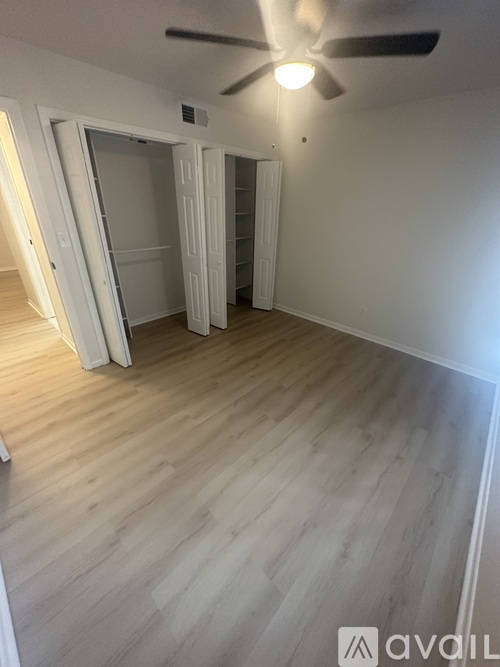 A room with a ceiling fan and light, and a doorway leading to another room.
