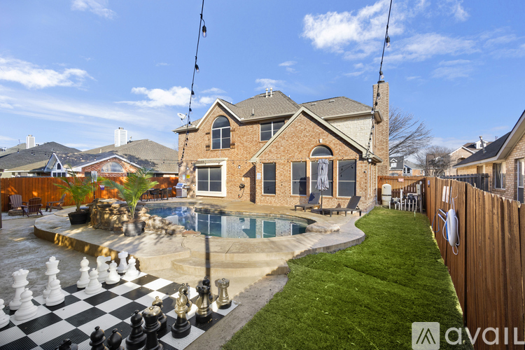 A house with a pool and a chess board in the backyard.