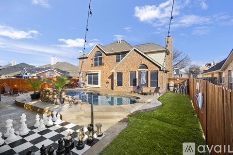 A house with a pool and a chess board in the backyard.