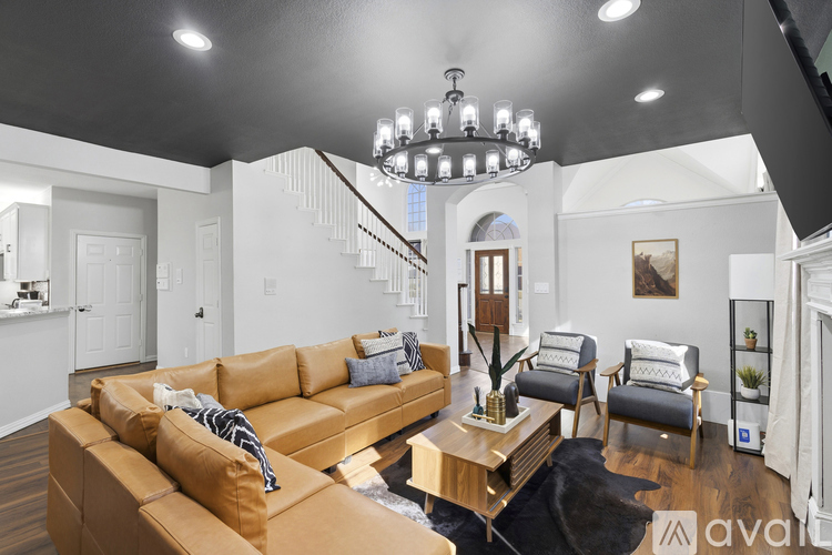 A living room with a tan couch and a chandelier.