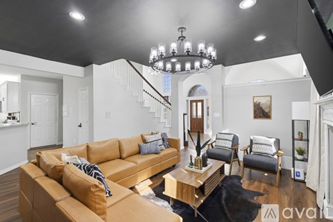 A living room with a tan couch and a chandelier.
