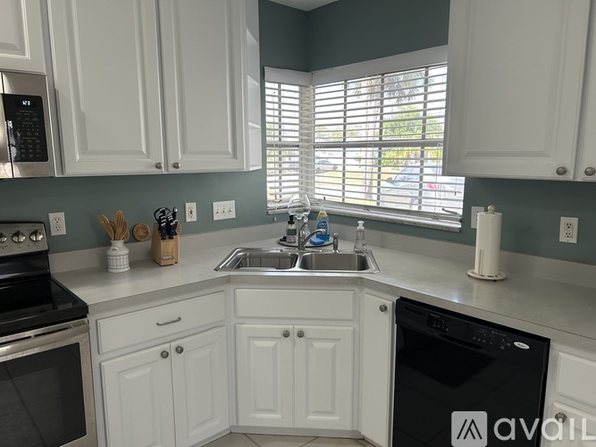 A kitchen with white cabinets and a black dishwasher.