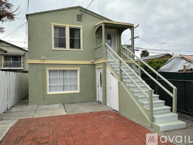 A house with a green exterior and a staircase leading to the front door.
