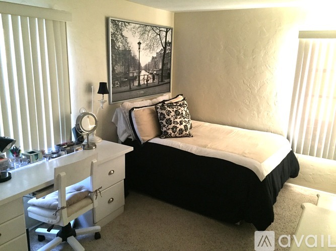 A bedroom with a bed, desk, chair, and a picture on the wall.