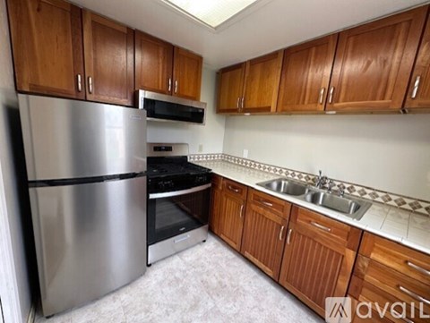 A kitchen with wooden cabinets and a stainless steel refrigerator.