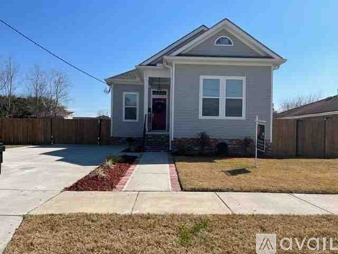 A gray house with a red door and a small front yard.