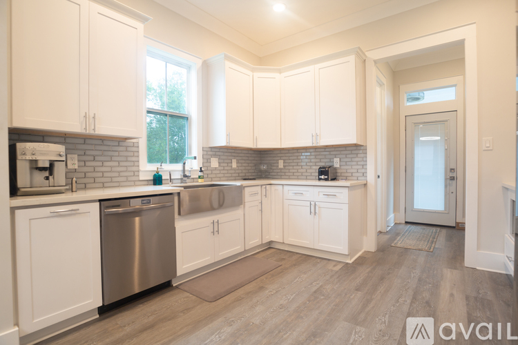 A kitchen with white cabinets and a wooden floor.