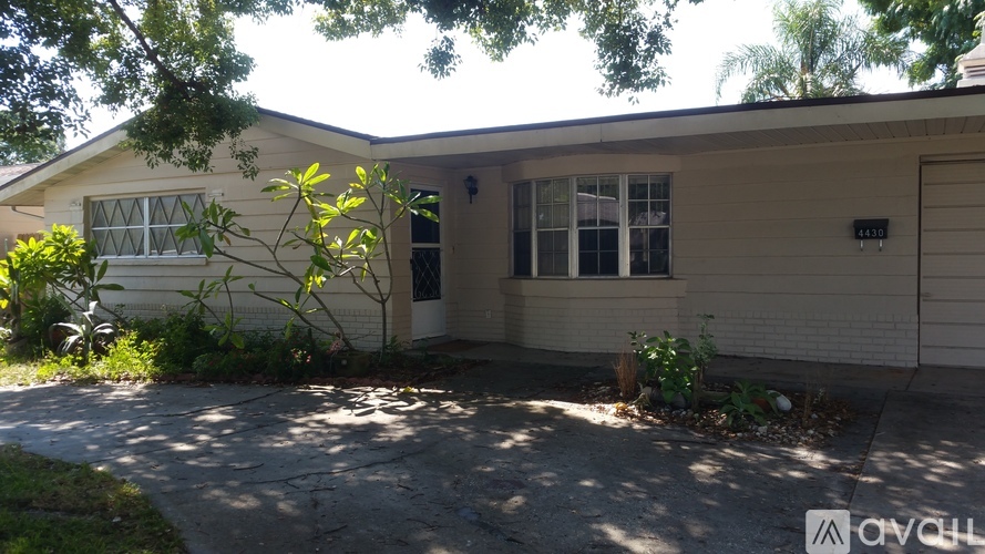 A house with a driveway and a tree in front.