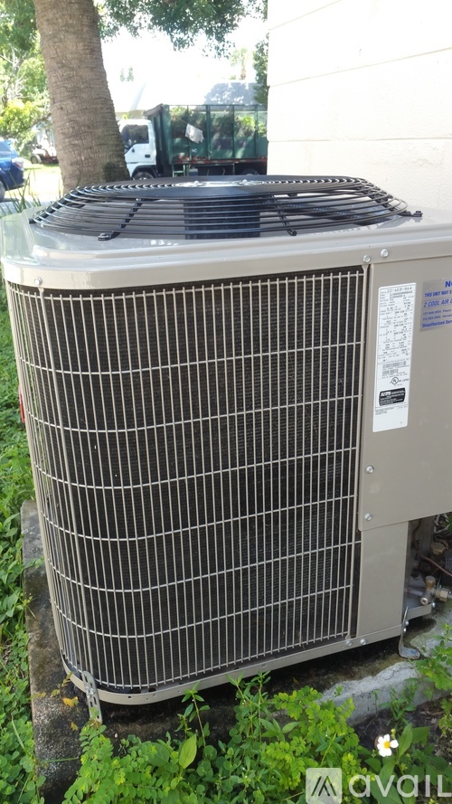 A large outdoor air conditioning unit sits on a grassy area.