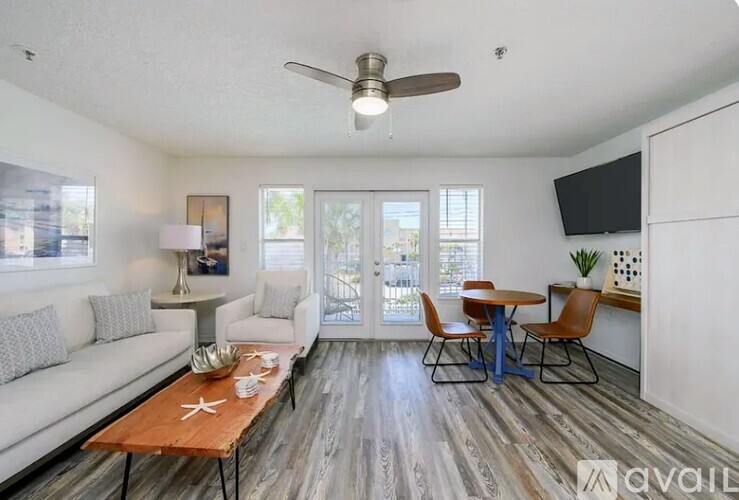 A living room with a white couch, a wooden coffee table, and a ceiling fan.