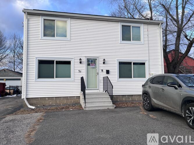 A two-story house with a car parked in front.