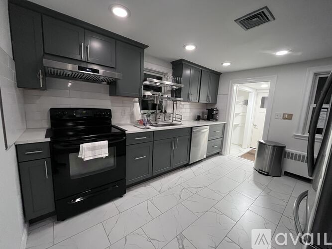 A modern kitchen with black cabinets and a black stove top oven.