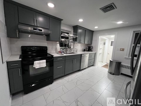 A modern kitchen with black cabinets and a black stove top oven.