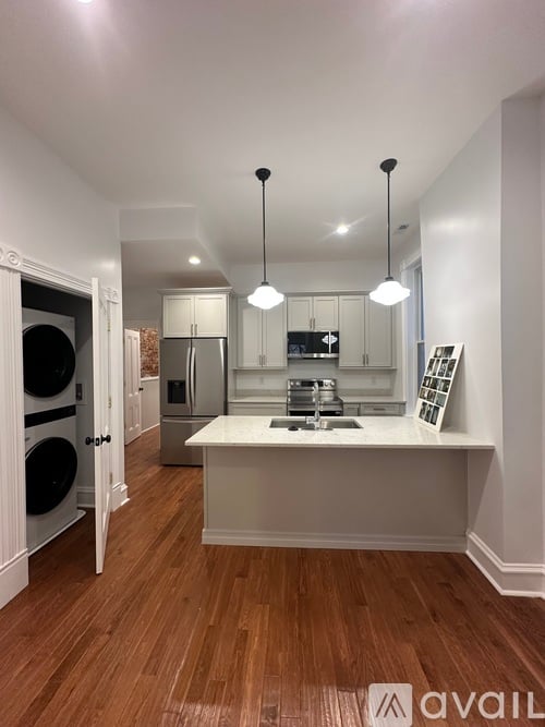 A kitchen with a white countertop and wooden flooring.