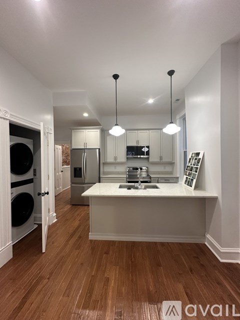 A kitchen with a white countertop and wooden flooring.