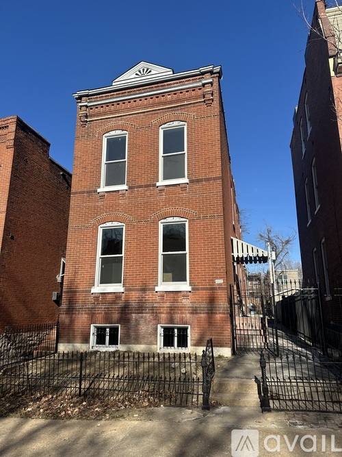 A red brick building with a black iron fence in front.