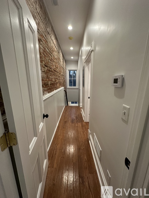 A long hallway with a brick wall on the side and white walls on the other.