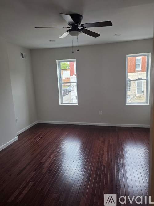 A room with a ceiling fan and two windows.
