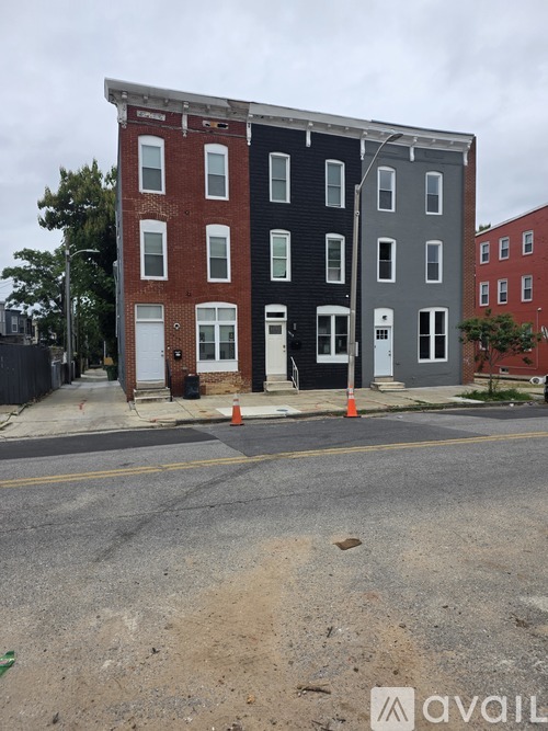 A street view of a multi-story building with a red brick facade and a grey facade.