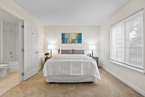 A bedroom with a large bed and a painting on the wall.