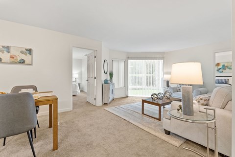A living room with a grey chair and a table with a lamp on it.