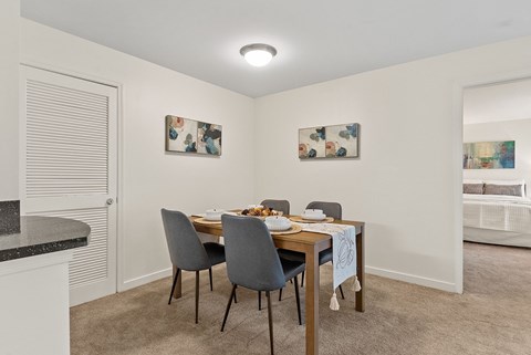 A dining room with a table set for two and two chairs.