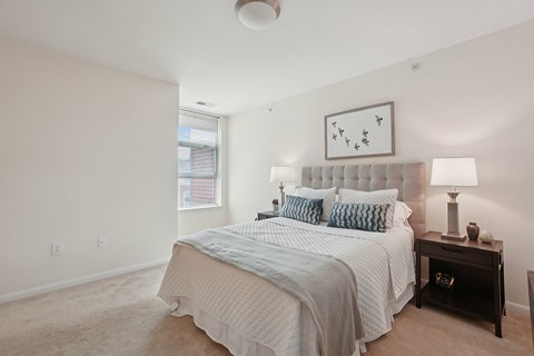 A bedroom with a large bed and a nightstand with a lamp.