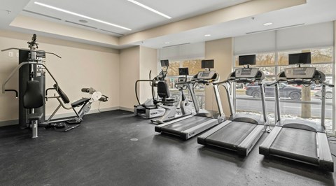 A gym with treadmills, elliptical machines, and a weight machine.